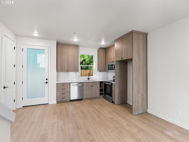 kitchen featuring backsplash, sink, light wood-type flooring, and stainless steel appliances