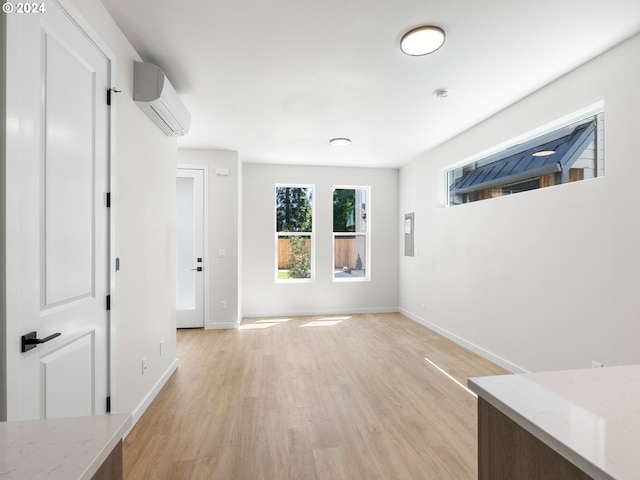 interior space with a wall mounted air conditioner and light hardwood / wood-style flooring