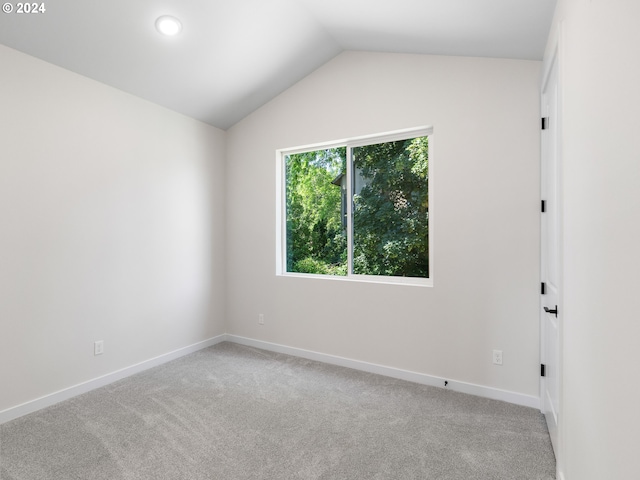 carpeted spare room featuring vaulted ceiling