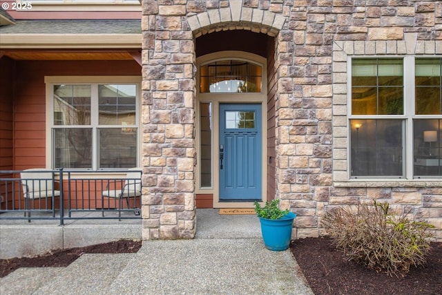 property entrance featuring a shingled roof and stone siding