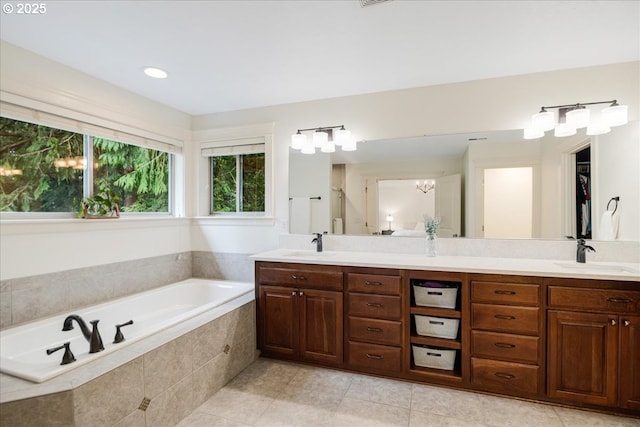 full bathroom with double vanity, a garden tub, a sink, and tile patterned floors