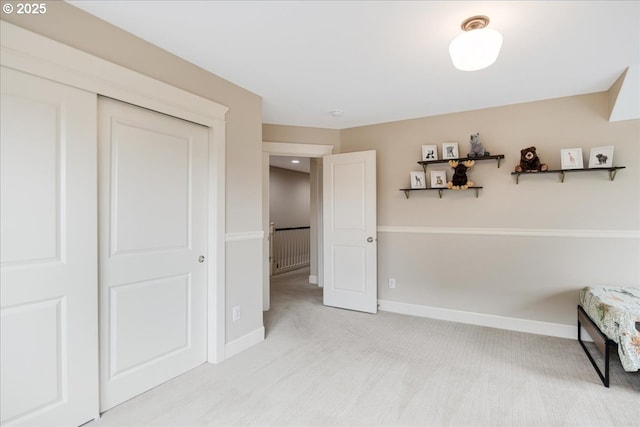 bedroom with a closet, light carpet, and baseboards