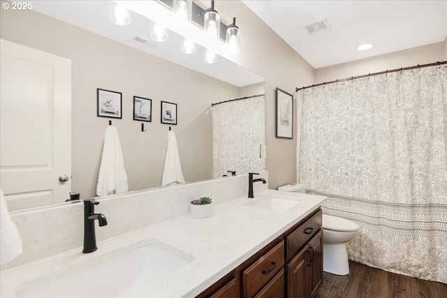 bathroom with visible vents, a sink, toilet, and wood finished floors