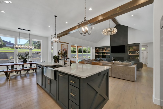 kitchen with a kitchen island with sink, sink, stainless steel dishwasher, built in features, and a fireplace