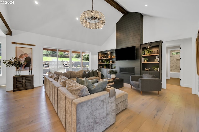 living room with beamed ceiling, a large fireplace, light hardwood / wood-style flooring, and a notable chandelier