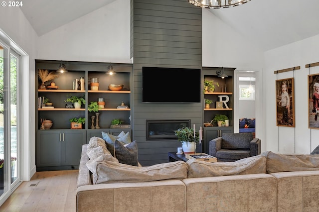 living room featuring a fireplace, a chandelier, lofted ceiling, and light hardwood / wood-style flooring