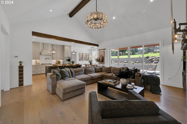 living room with beamed ceiling, high vaulted ceiling, an inviting chandelier, and light hardwood / wood-style flooring