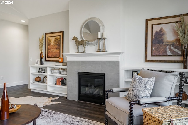 living room featuring a tile fireplace, vaulted ceiling, and dark hardwood / wood-style floors