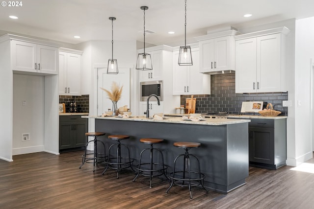 kitchen with white cabinets, a kitchen island with sink, and pendant lighting