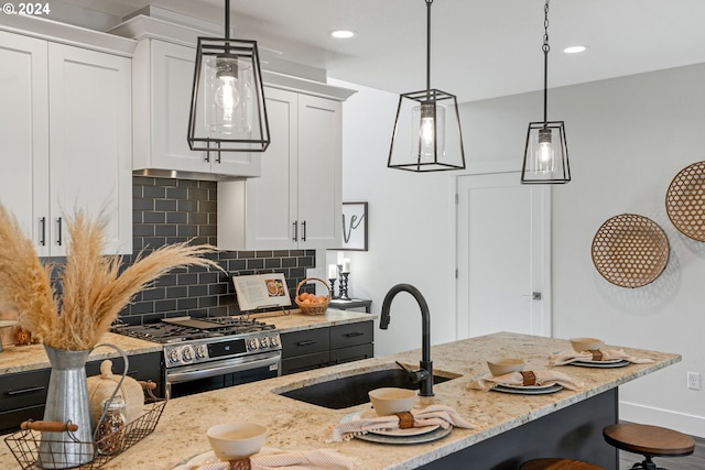 kitchen with white cabinets, sink, stainless steel range with gas cooktop, and decorative light fixtures