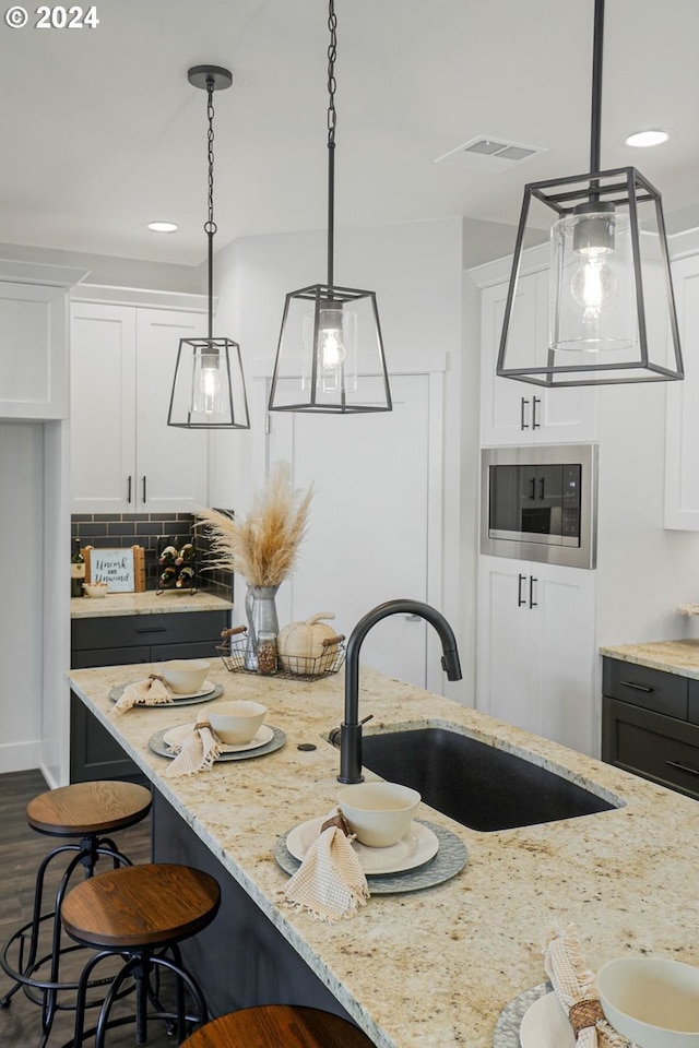 kitchen featuring white cabinets, sink, and stainless steel microwave