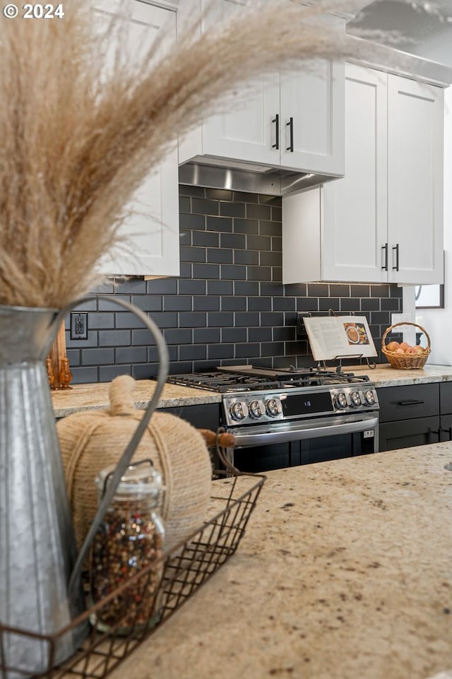 kitchen featuring white cabinetry, light stone countertops, backsplash, and stainless steel gas range oven