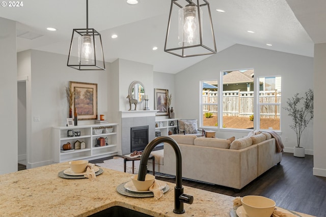 living room featuring a tile fireplace, vaulted ceiling, and dark hardwood / wood-style flooring