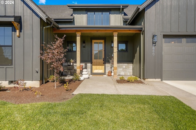 view of exterior entry featuring a garage, a lawn, and a porch