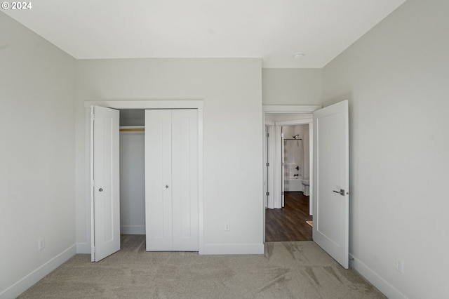 unfurnished bedroom featuring a closet and light colored carpet