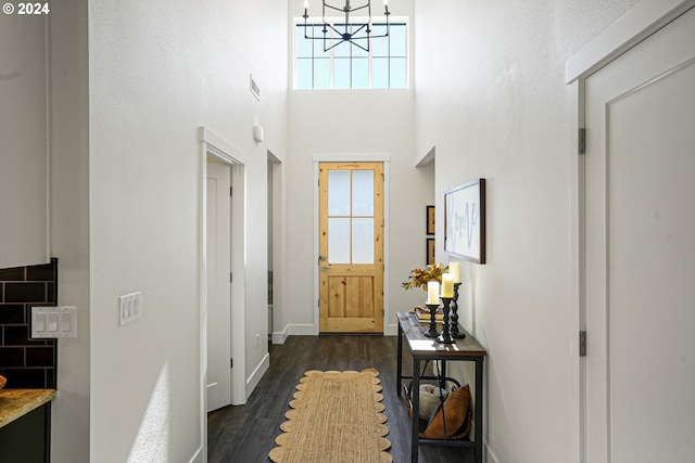 doorway to outside with a chandelier, dark wood-type flooring, and a towering ceiling