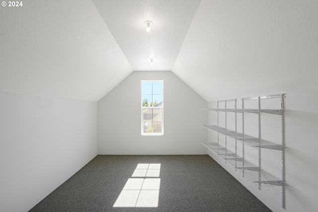 bonus room featuring vaulted ceiling and dark colored carpet