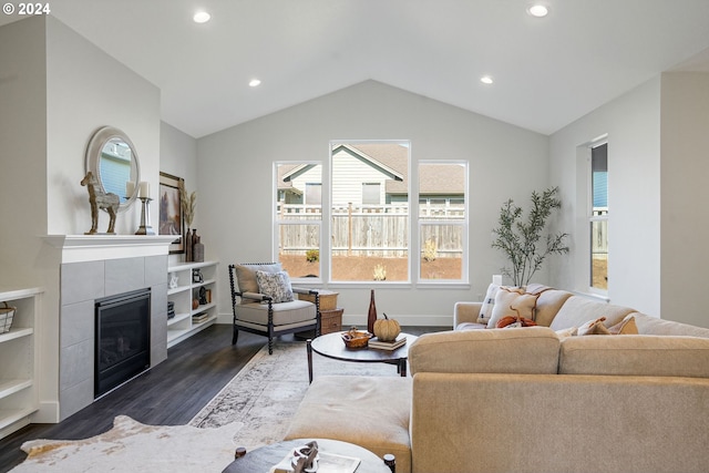 living room with dark hardwood / wood-style flooring, a tile fireplace, and vaulted ceiling