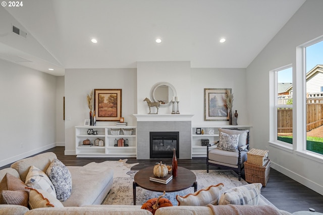 living room featuring a fireplace, dark wood-type flooring, vaulted ceiling, and a wealth of natural light