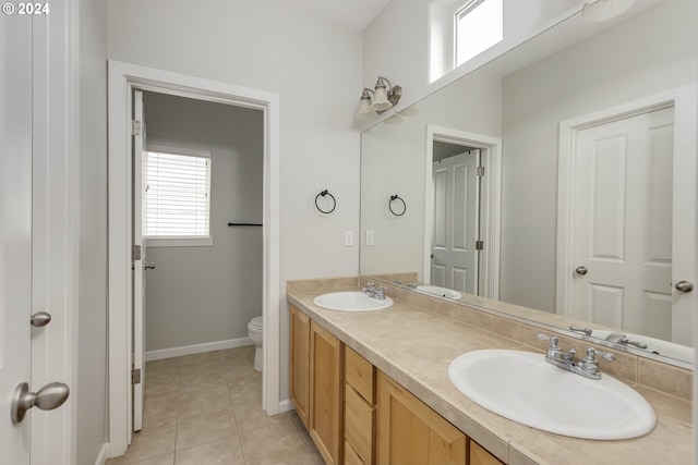 bathroom featuring tile patterned floors, double vanity, toilet, and a sink