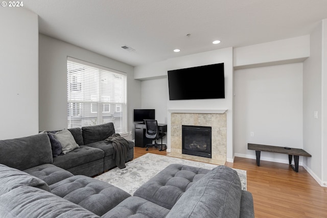 living room featuring hardwood / wood-style flooring, a tiled fireplace, and a textured ceiling