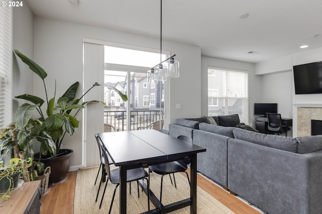 dining area featuring a tile fireplace and light wood-type flooring