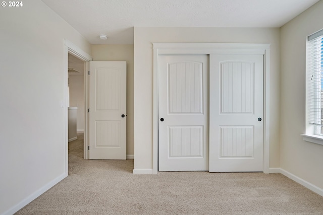 unfurnished bedroom featuring a closet and light colored carpet