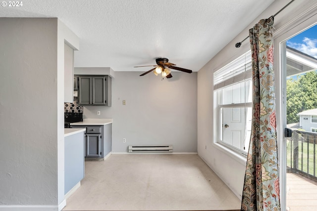 interior space featuring ceiling fan, a baseboard heating unit, a textured ceiling, and gray cabinets