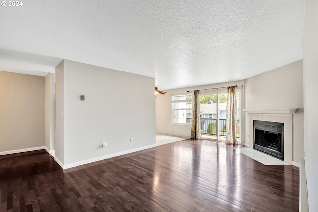 unfurnished living room with ceiling fan, a textured ceiling, a tile fireplace, and light wood-type flooring