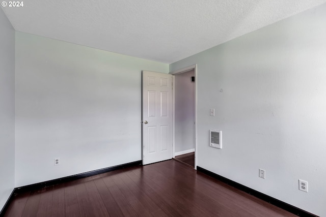 unfurnished room featuring dark wood-type flooring and a textured ceiling