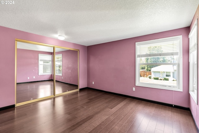 unfurnished room with dark wood-type flooring and a textured ceiling