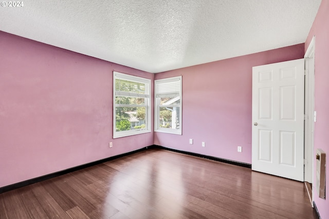 empty room with a textured ceiling and wood-type flooring