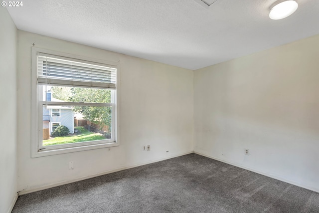 unfurnished room with dark colored carpet and a textured ceiling