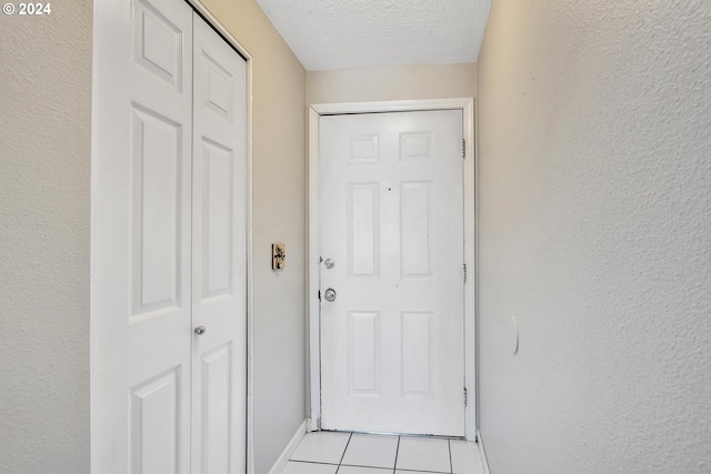 doorway with light tile patterned floors and a textured ceiling