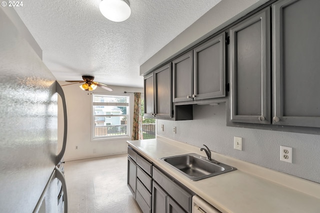 kitchen featuring ceiling fan, sink, gray cabinets, a textured ceiling, and refrigerator