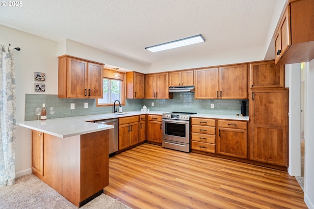 3427 NE 32nd Pl, Portland, OR 97212 - kitchen with appliances with stainless steel finishes, a sink, a peninsula, brown cabinets, and backsplash