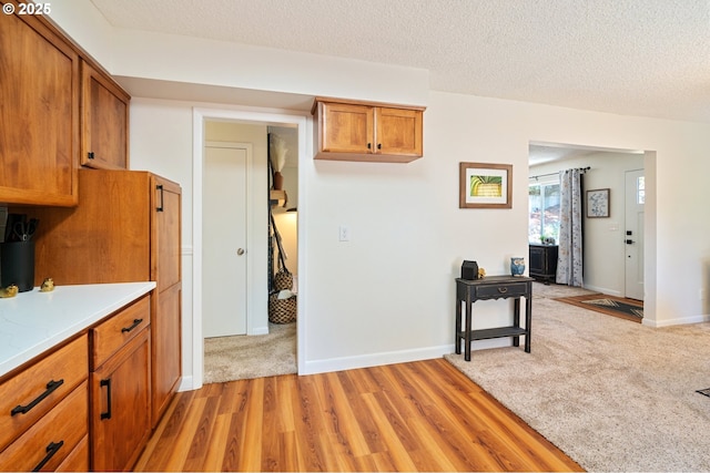 3427 NE 32nd Pl, Portland, OR 97212 - kitchen featuring brown cabinetry, light countertops, light wood-type flooring, baseboards, and a textured ceiling