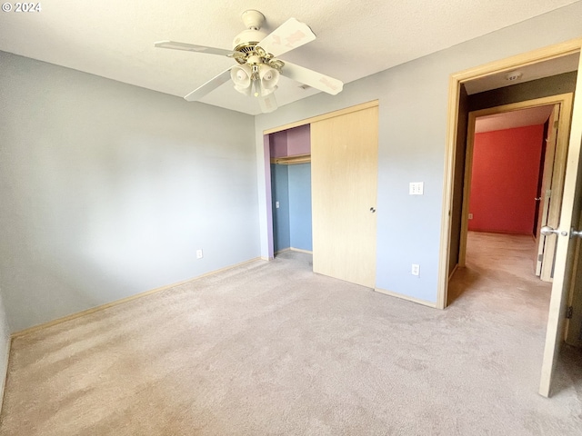 unfurnished bedroom featuring ceiling fan, a closet, and light carpet