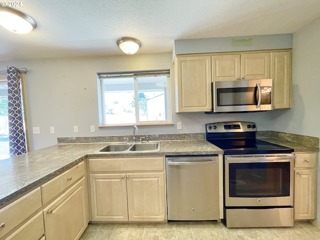 kitchen with light brown cabinets, sink, kitchen peninsula, a textured ceiling, and appliances with stainless steel finishes