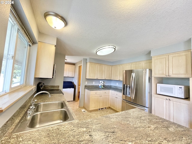 kitchen featuring a textured ceiling, sink, stainless steel refrigerator with ice dispenser, and range