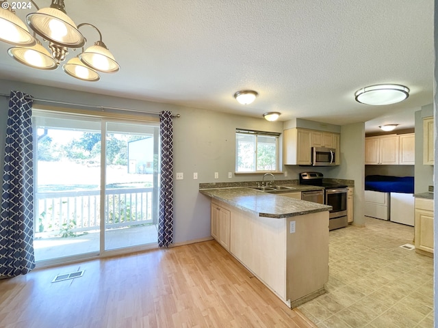 kitchen with sink, stainless steel appliances, kitchen peninsula, a textured ceiling, and decorative light fixtures