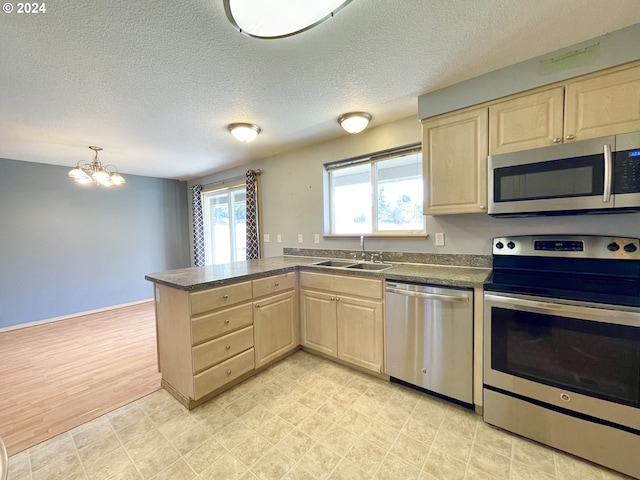 kitchen featuring sink, light brown cabinets, an inviting chandelier, kitchen peninsula, and appliances with stainless steel finishes