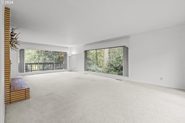 unfurnished living room featuring visible vents, carpet flooring, and a healthy amount of sunlight