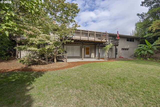 rear view of property featuring a garage, a patio area, a yard, and a deck