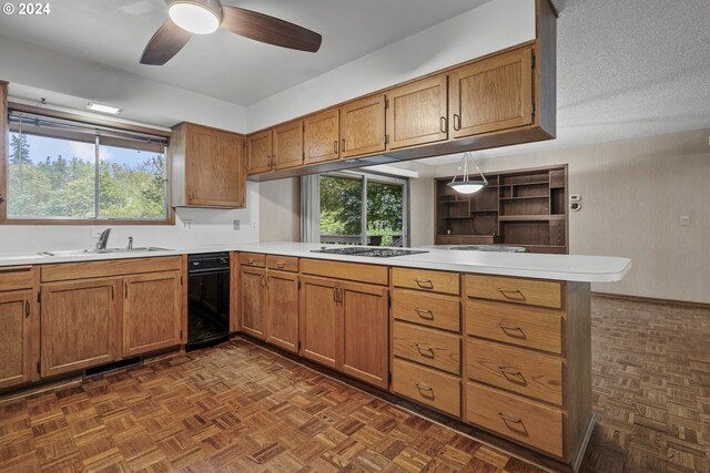 kitchen with a sink, a peninsula, light countertops, brown cabinets, and a ceiling fan