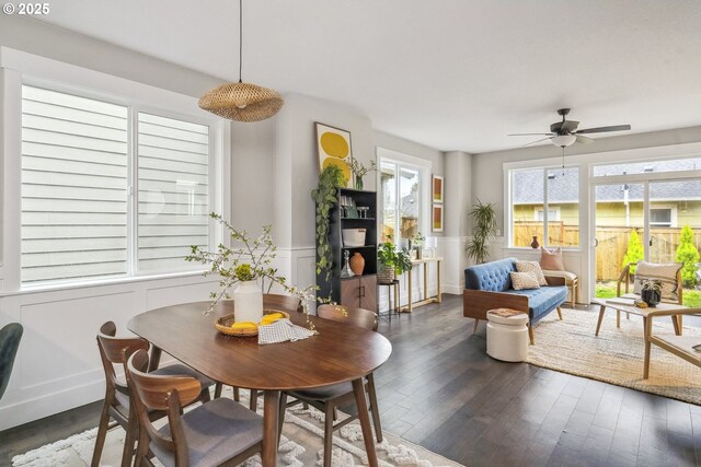 dining area featuring hardwood / wood-style floors, a decorative wall, a ceiling fan, and a wainscoted wall