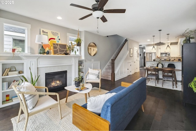 living area with stairs, recessed lighting, dark wood finished floors, and a tile fireplace