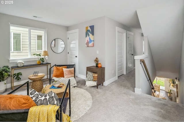 sitting room with an upstairs landing, visible vents, carpet flooring, and baseboards