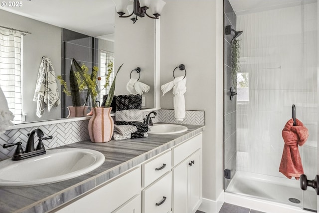 bathroom featuring decorative backsplash, a shower stall, double vanity, and a sink