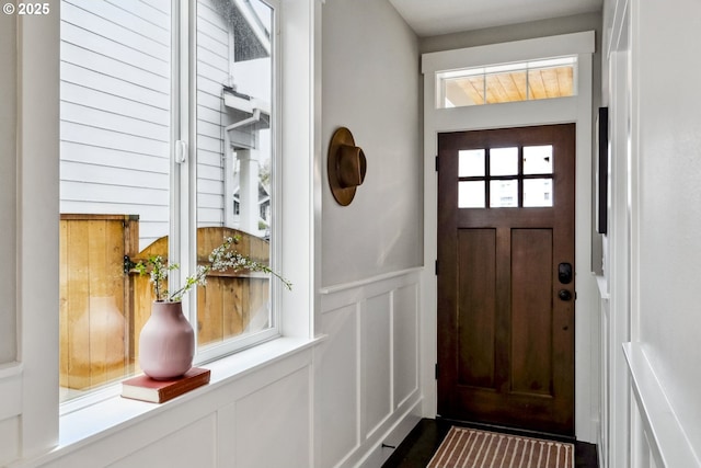 doorway to outside featuring a decorative wall and wainscoting